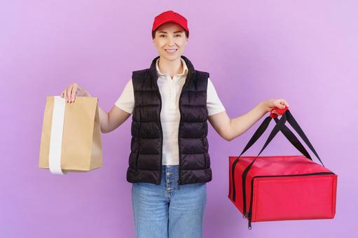 保温ピザバッグと紙袋を持つ笑顔の女性配達員 配達,フードデリバリー,デリバリーの写真素材