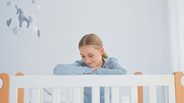 ベッドの柵に腕をのせ微笑み見ている女性 ベッドの柵に腕をのせ微笑み見ている女性の写真