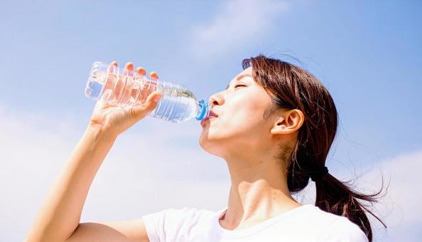 水分補給をするTシャツの女性 水分補給をするTシャツの女性の写真