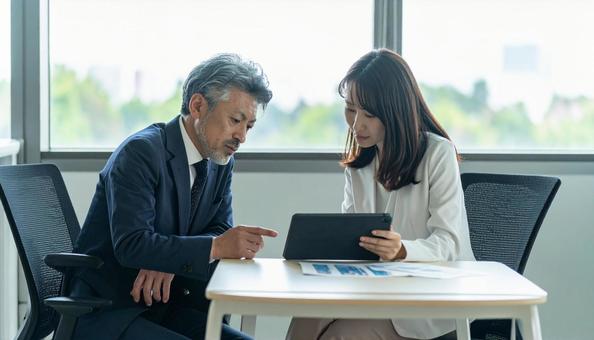 タブレットで打ち合わせするビジネス社員 タブレットで打ち合わせするビジネス社員の写真