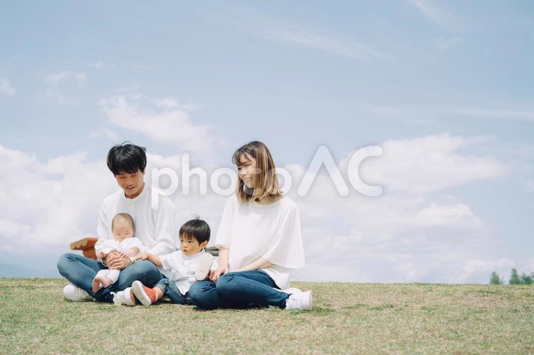 空と芝生に座る家族・ファミリー（4人） 家族,親子,赤ちゃんの写真素材