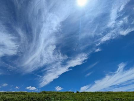 緑の土手と青い空に白く透き通ったすじ雲 緑の土手と青い空に白く透き通ったすじ雲の写真