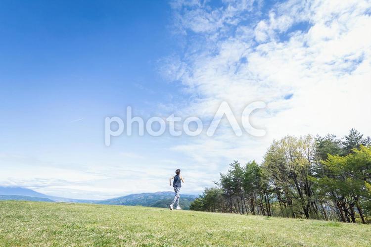 広い場所で運動する女性（走る・後ろ姿） 青空,運動,空の写真素材