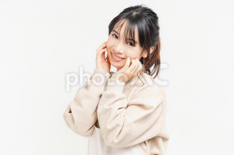 頬に手を当てる笑顔の若い女性 女性,頬,笑うの写真素材