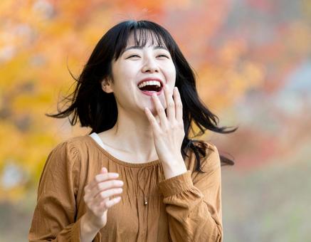 秋の公園で笑顔を見せる女性 秋の公園で笑顔を見せる女性の写真