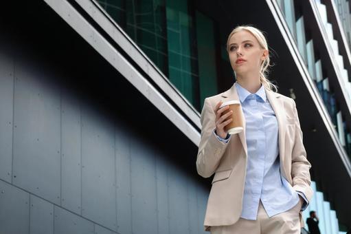オフィスビルの外でコーヒーを持って立っているビジネスウーマン ビジネスウーマン,ビジネス,女性の写真素材