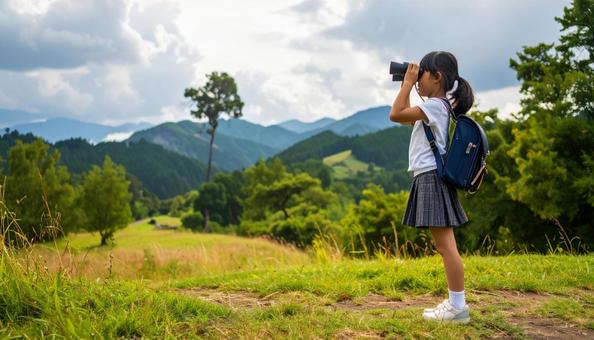 双眼鏡で遠くを眺める小学生の女の子 双眼鏡で遠くを眺める小学生の女の子の写真