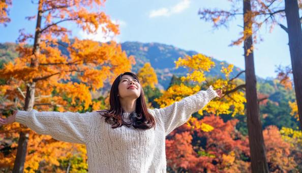 紅葉の中で深呼吸する秋服の日本人女性 紅葉の中で深呼吸する秋服の日本人女性の写真