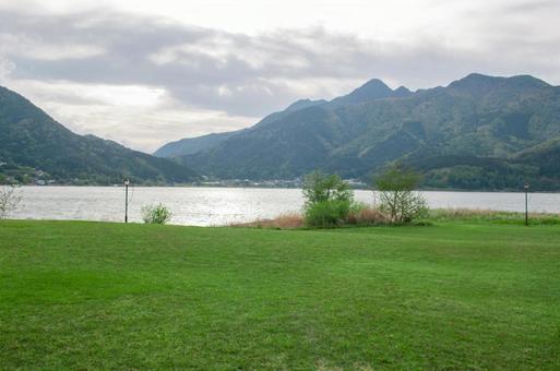 湖畔の芝生と山並み 湖畔の芝生と山並みの写真