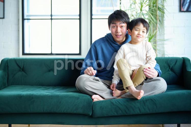 ソファーにあぐらで座って抱っこする親子 親子,男の子,小学生の写真素材