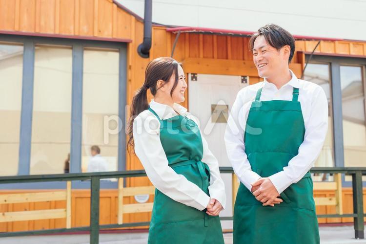 お店の前に立つエプロン姿の男女 カフェ,飲食店,ウェイトレスの写真素材