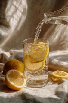 グラスに注がれる水と輝くレモンのスライス グラスに注がれる水と輝くレモンのスライスの写真