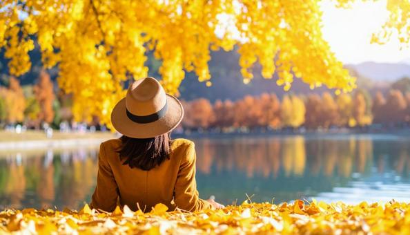 銀杏並木と湖のほとりでくつろぐ女性の写真