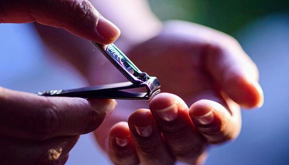 爪切りで爪を切る女性の手元の写真