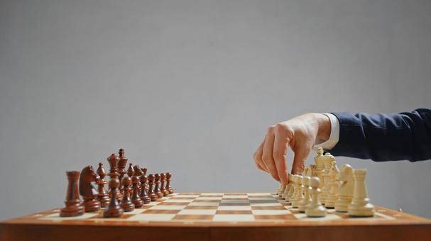 チェスをするスーツを着た男性の手(グレー背景) チェスをするスーツを着た男性の手(グレー背景)の写真