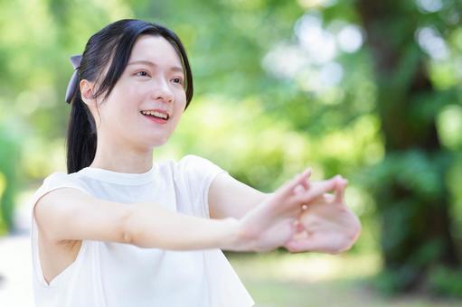 白いノースリーブワンピースの女性が腕を伸ばすの写真