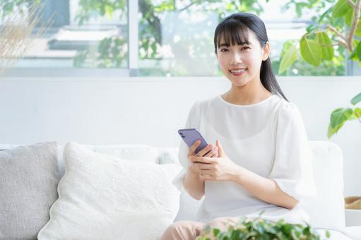 リビングでスマホを見る若い女性 リビングでスマホを見る若い女性 女性,リビング,ライフスタイルの写真素材