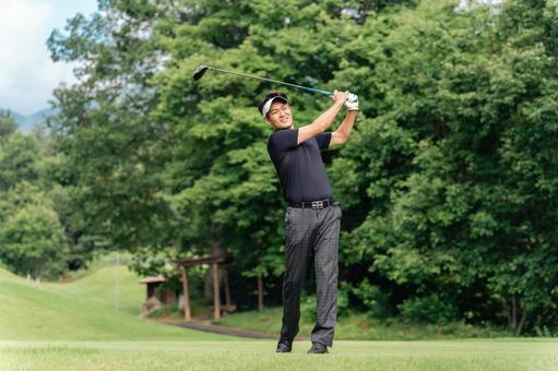ゴルフ場でゴルフをするゴルファーの男性の写真