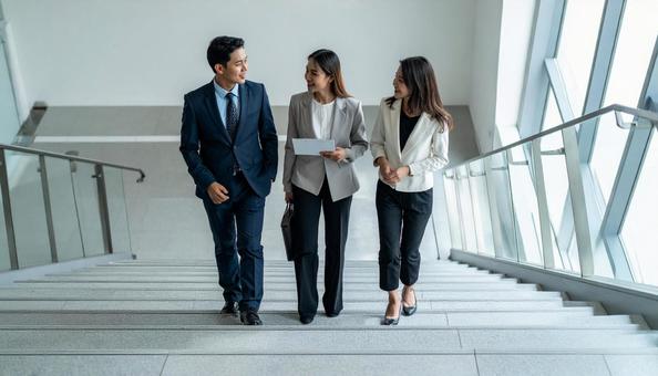 オフィスの階段で話をするビジネスパーソン オフィスの階段で話をするビジネスパーソンの写真