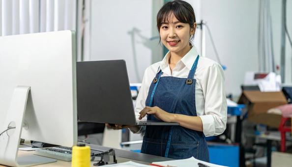 工場の三次元測定機を使う作業服の女性の写真