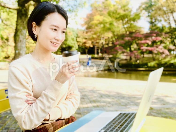 公園でパソコン作業をする笑顔の女性 女性,pc,web会議の写真素材
