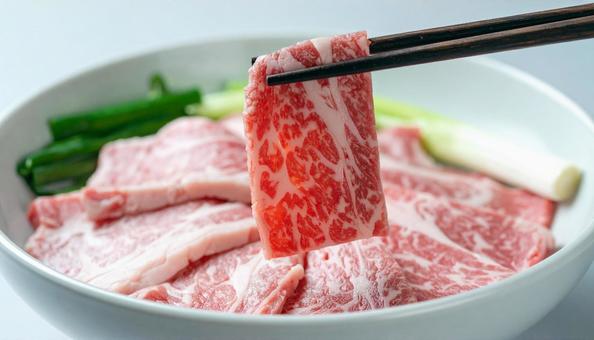 焼肉用の生肉を箸でつまむ 焼肉用の生肉を箸でつまむの写真