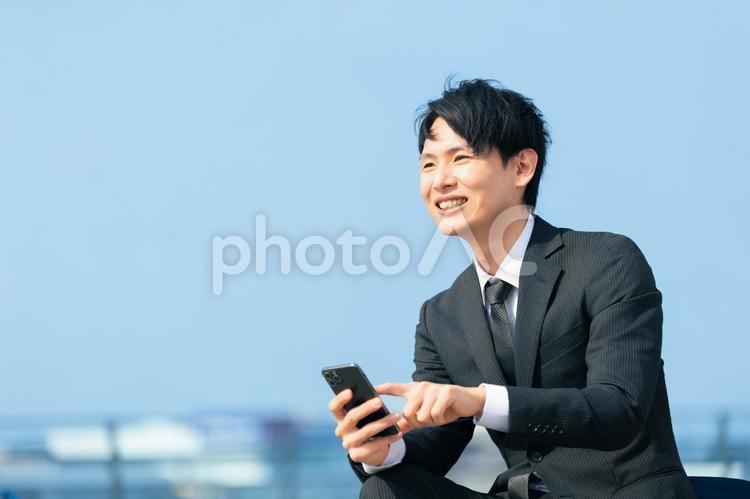 スマホを使う笑顔の男性ビジネスマン 男性,スマホ,スマートフォンの写真素材