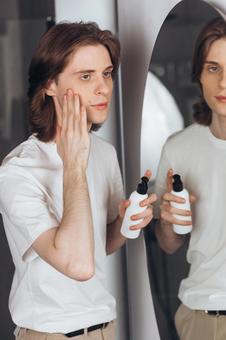 楕円形の鏡を見ながらスキンケアする若い男性 男性,外国人,欧米人の写真素材