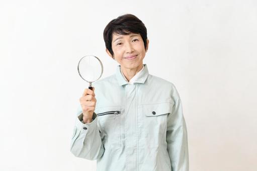 虫眼鏡を持つカメラ目線の作業服の中年女性 作業員,虫眼鏡,ミドルの写真素材