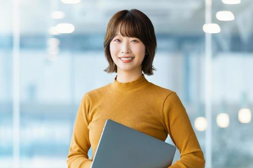 ノートパソコンを持つ笑顔の女性 ノートパソコンを持つ笑顔の女性 女性,パソコン,笑顔の写真素材