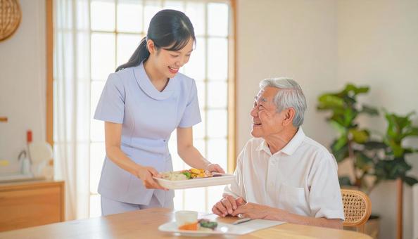 笑顔で食事を運ぶ女性介護士と高齢男性 笑顔で食事を運ぶ女性介護士と高齢男性の写真