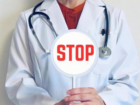 STOPと書かれた札を持った女性医師 ドクターストップ,ストップ,ダメの写真素材