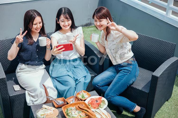 屋上でパーティーをする女性たち（スマホ） 女子会,ランチ,スマホの写真素材