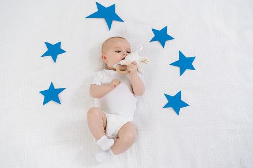 星に囲まれ玩具を口に入れようとしている赤ちゃん 星に囲まれ玩具を口に入れようとしている赤ちゃん 赤ちゃん,かわいい,仰向けの写真素材