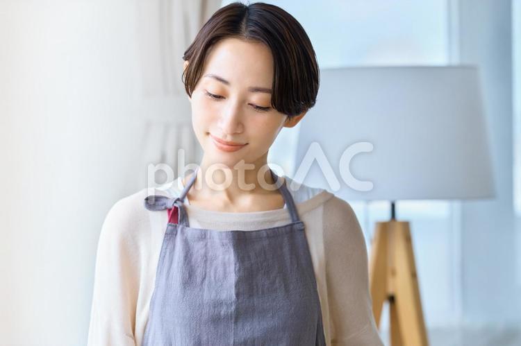 下を見る主婦　エプロンの女性　部屋 主婦,下を向く,リビングの写真素材