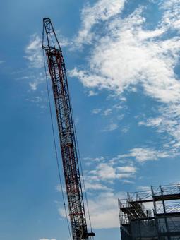 空へ伸びるクレーンと建設現場の風景 クレーン,建設現場,縦構図の写真素材