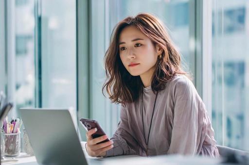 スマホを見るビジネス女性 スマホを見るビジネス女性の写真
