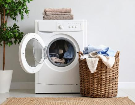 洗濯機と洗濯物が溢れて洗濯カゴの写真