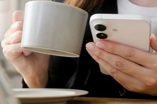 スマホとコーヒーカップを持つ女性 スマホ,女性,カフェの写真素材