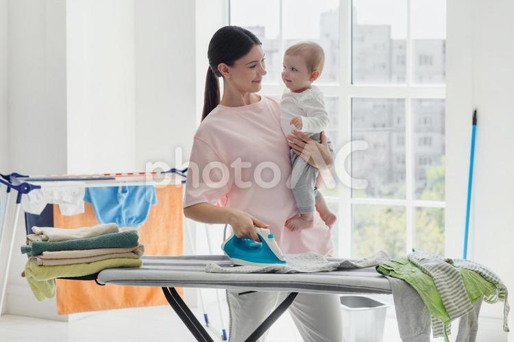 赤ちゃんを抱っこしてアイロンする親子 親子,女性,人物の写真素材