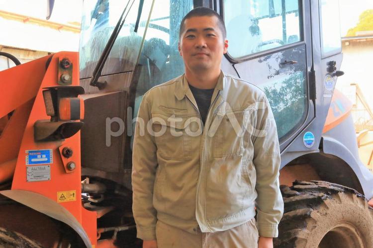 ホイルローダーと作業着の男性 作業服,現場,坊主の写真素材