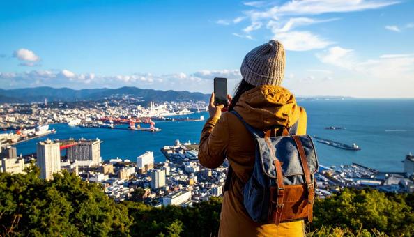 海の向こうを携帯で撮影する観光客の女性 海の向こうを携帯で撮影する観光客の女性の写真