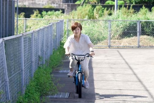 <人物>広場で自転車を練習する笑顔の女性 <人物>広場で自転車を練習する笑顔の女性 女性,笑顔,自転車の写真素材