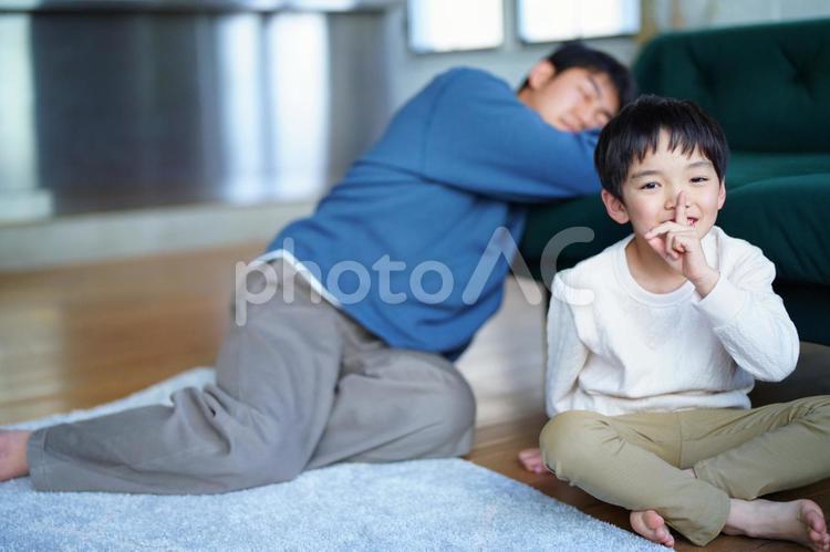 静かにのジェスチャーをする男の子と寝ている男性 親子,男の子,小学生の写真素材