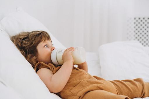 両手で哺乳瓶を持ち飲んでいる子供 両手で哺乳瓶を持ち飲んでいる子供 赤ちゃん,哺乳瓶,ミルクの写真素材
