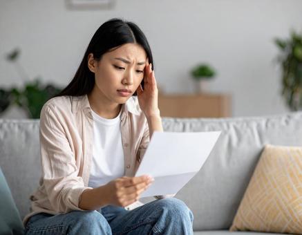 請求書を見て悩んでいる女性 請求書を見て悩んでいる女性の写真