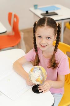 地球儀を持ってカメラ目線の女の子 女の子,子ども,人物の写真素材