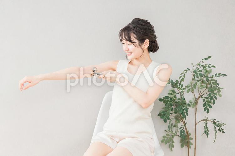 マッサージローラーで二の腕をケアする女性 二の腕,マッサージ,マッサージローラーの写真素材