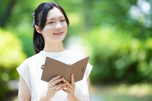 白いノースリーブワンピースの女性が本を持つの写真