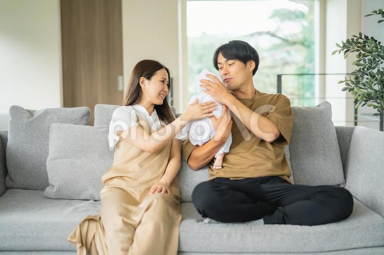 ソファで赤ちゃんを抱く男女 赤ちゃん,育児,新婚の写真素材